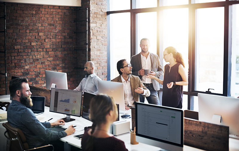 a photo showing a team working away in an office with three employees discussing an effective sales strategy between themselves 